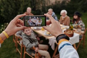 Person holding smartphone, taking picture of people at a table