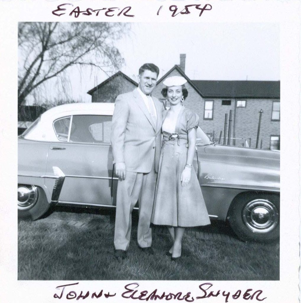 Married couple 1954 in front of car and house