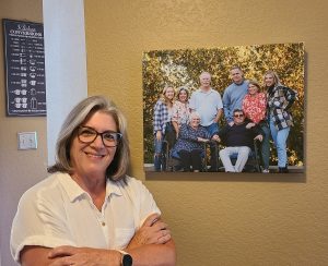 Woman wearing glasses standing in front of printed photo on wall
