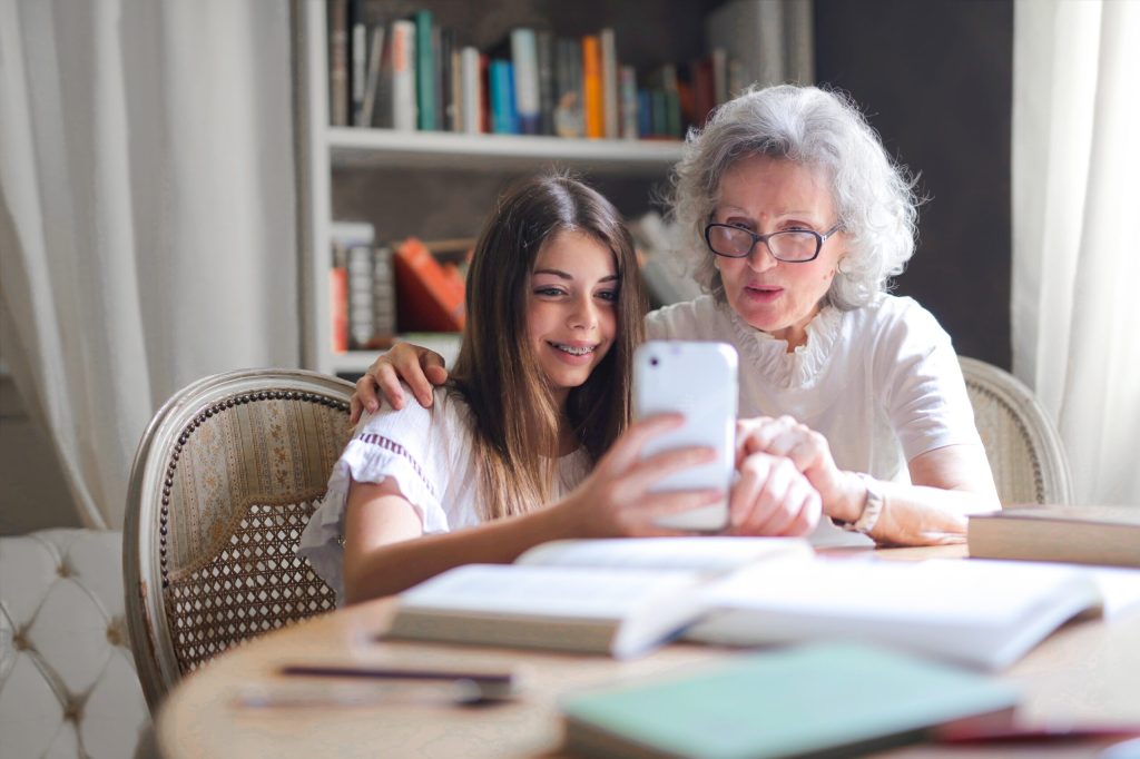 Girl looking t smartphone screen with white-haired woman