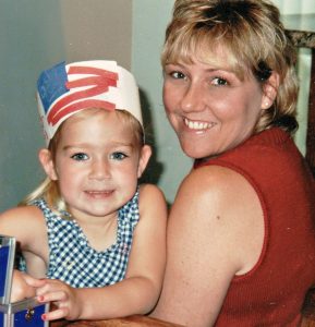 Young girl in red and white hat with young mother.