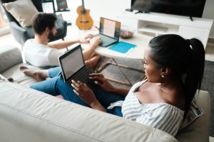 Woman in foreground on laptop, man in background on laptop