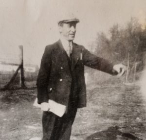 Man in 3 piece suit outdoors, pointing