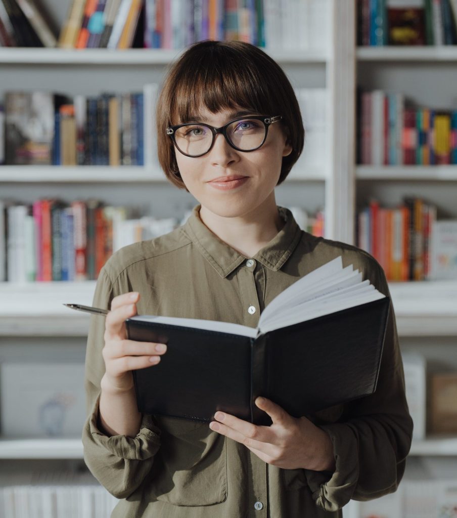 Woman glasses, green shirt, holding book