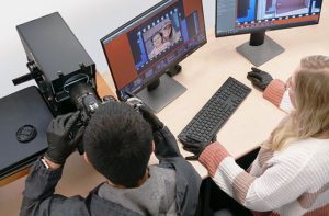 Man and woman sitting at camera and computer with images