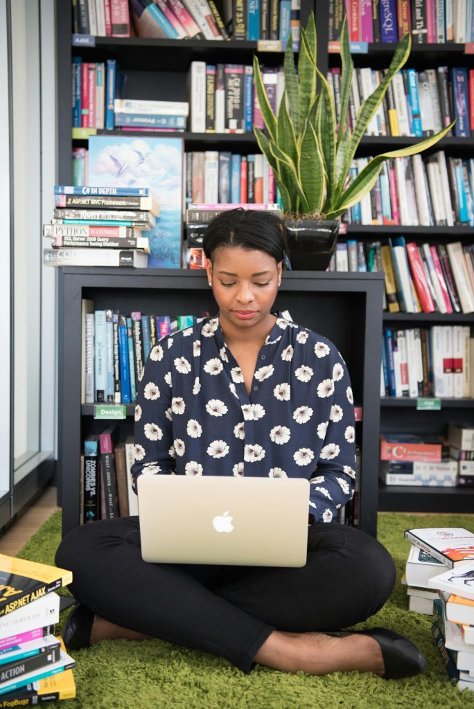 Woman sitting on laptop in front of books