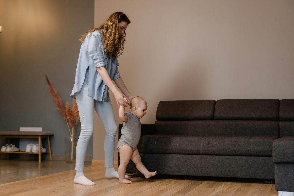 Woman holding hands of toddler while walking