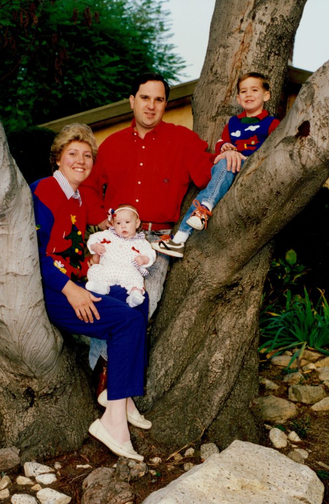 Young woman, left, with man and two children posing by a tree